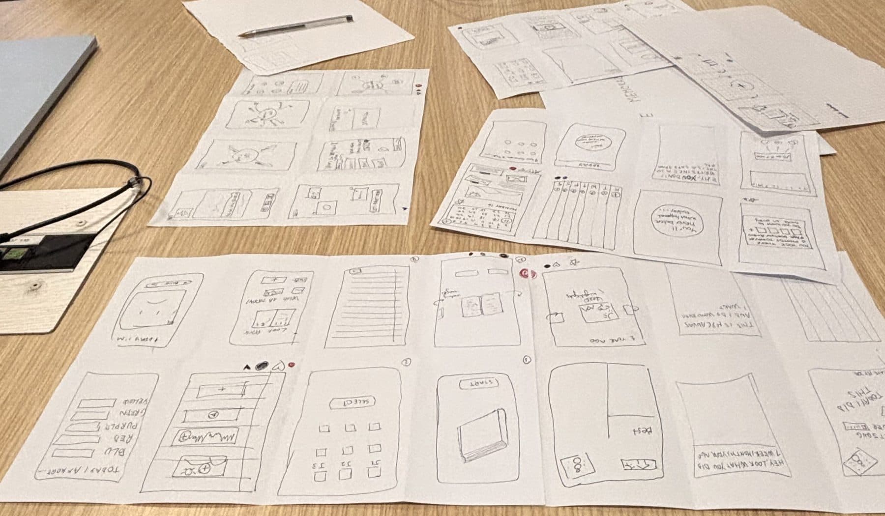 Paper sketches of Memori screens spread across a table